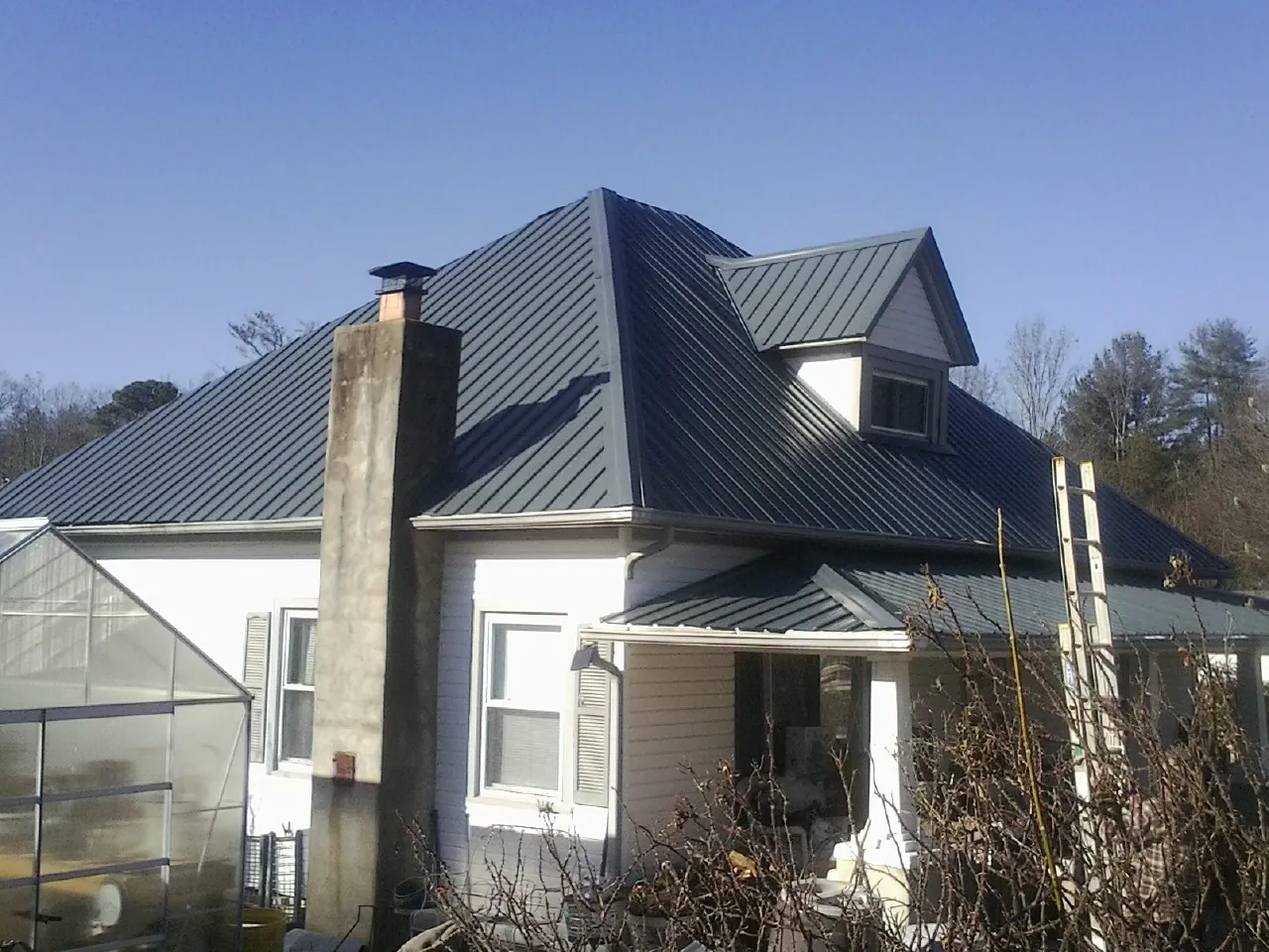 Dark blue standing seam metal roof on a white farmhouse with dormer — Slate & Tile Roof Repair by Roofing Brothers in Callao