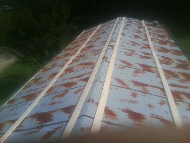 Rusted metal roof panels with new wood purlins before replacement — Storm Damage Roof Repair in Callao by Roofing Brothers