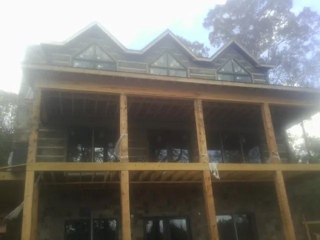 Dormers and porch framing on a large log home under construction — Roof Coating work by our crew in Callao