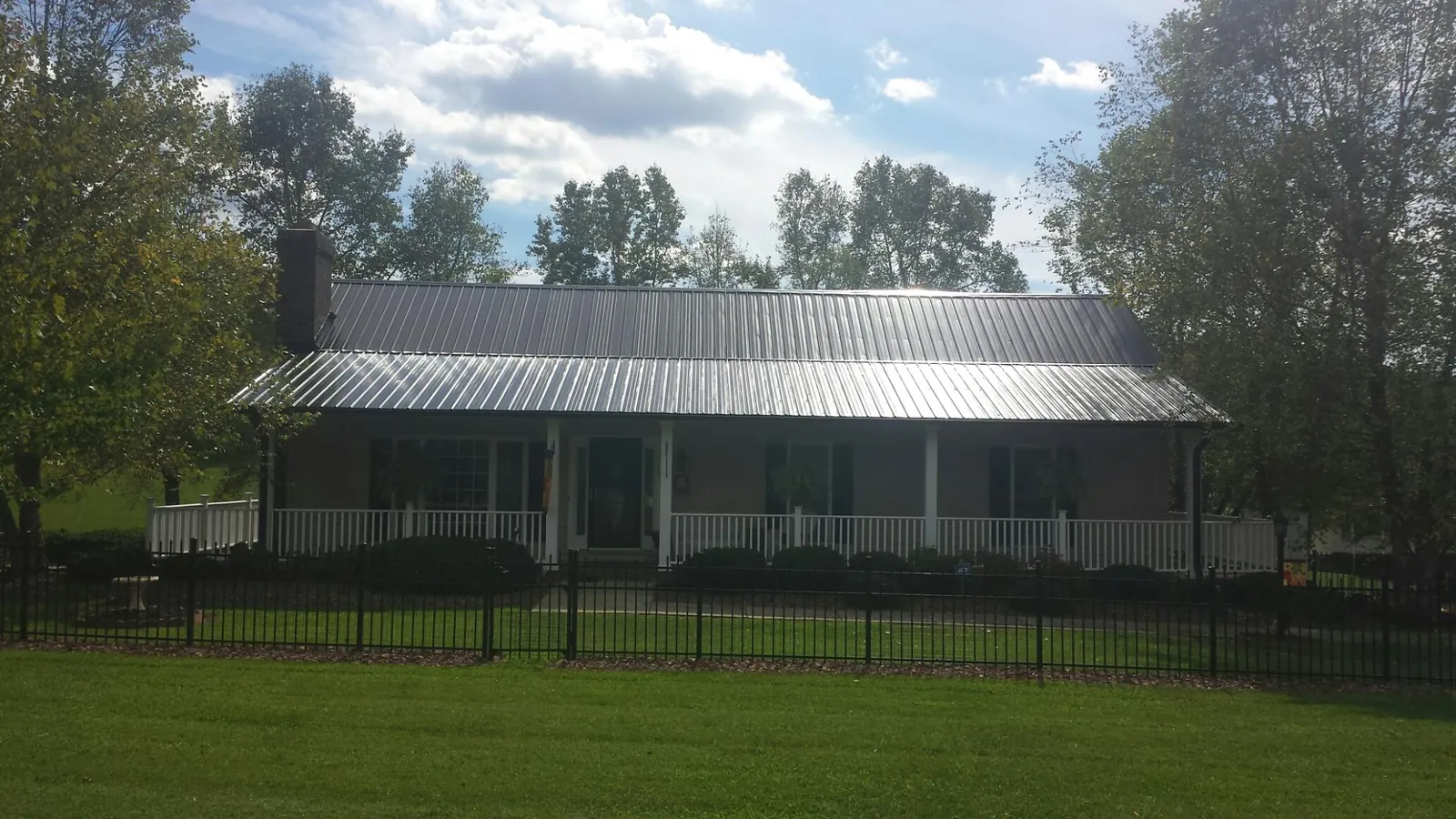 Gray metal roof on a brick ranch with a full width front porch — Gutter Guard Installation work by our crew in Callao