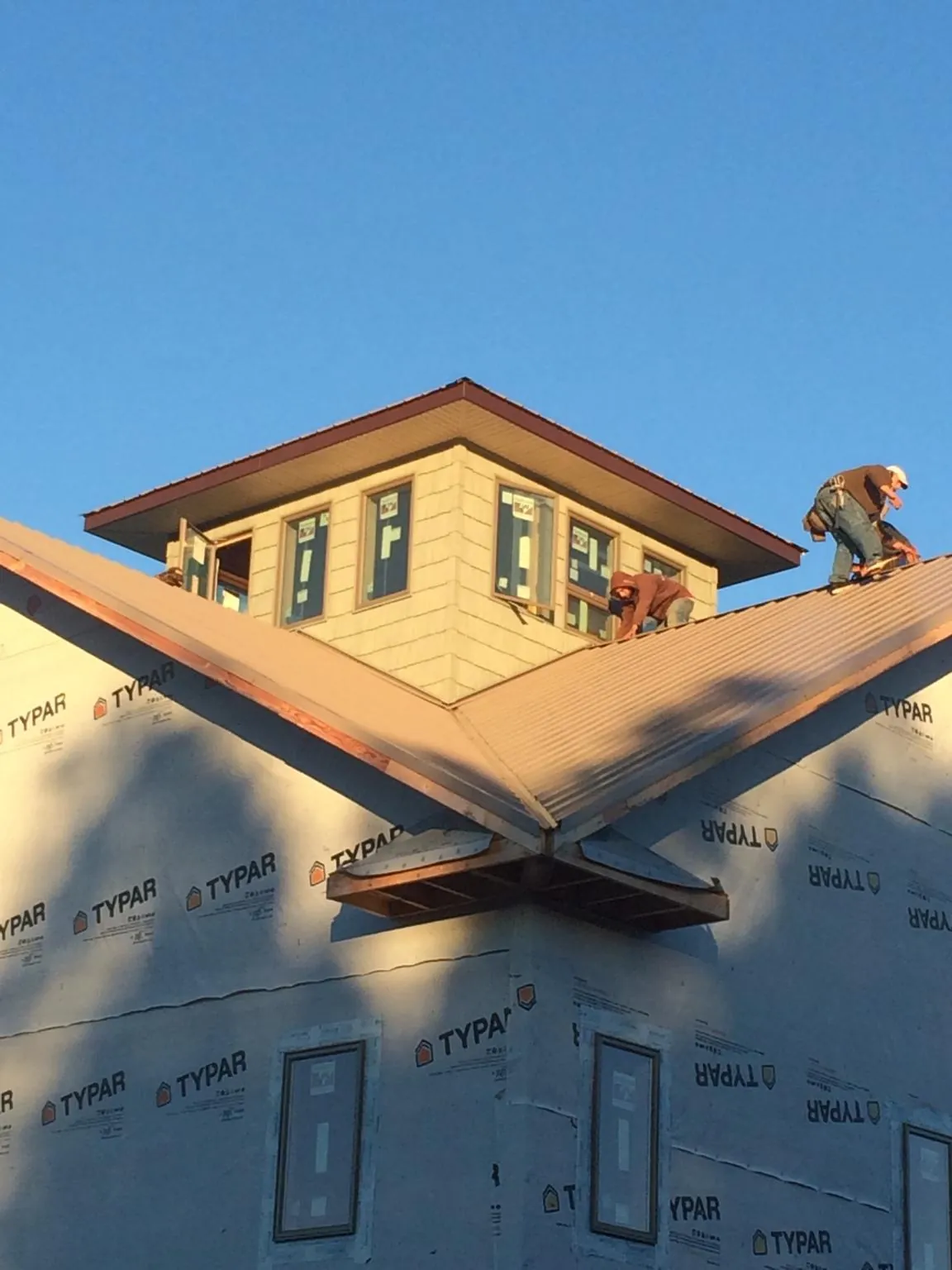 Roofers working around a rooftop cupola on a new metal roof at sunset — Roof Waterproofing in Callao by Roofing Brothers